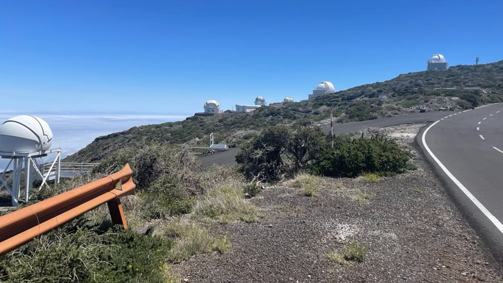 A photo of half a dozen telescopes at the top of a mountain