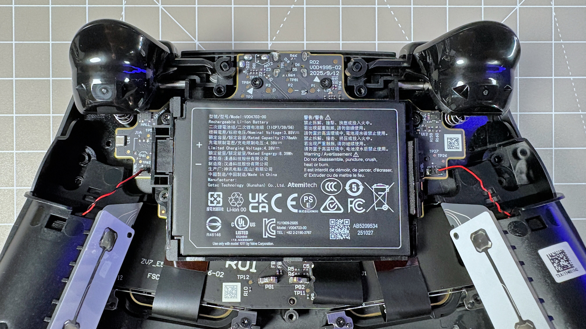 The Steam Controller on a desk during a teardown, with various parts removed.
