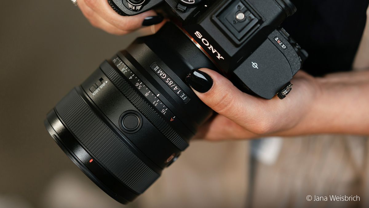 Sony FE 85mm f/1.4 GM II lens attached to a camera and held in a pair of hands