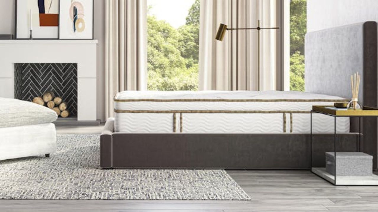 The Saatva Latex Hybrid Mattress on a bed against a wall with curtains and a fireplace.