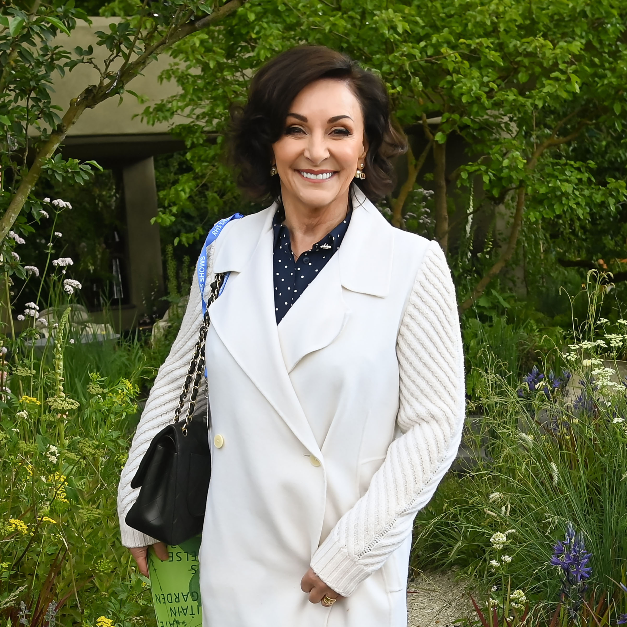 Shirley Ballas in white coat, with blue polka dot shirt underneath at Chelsea Flower Show.