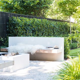 garden with grey fence, a living wall, white gravel and wooden seating