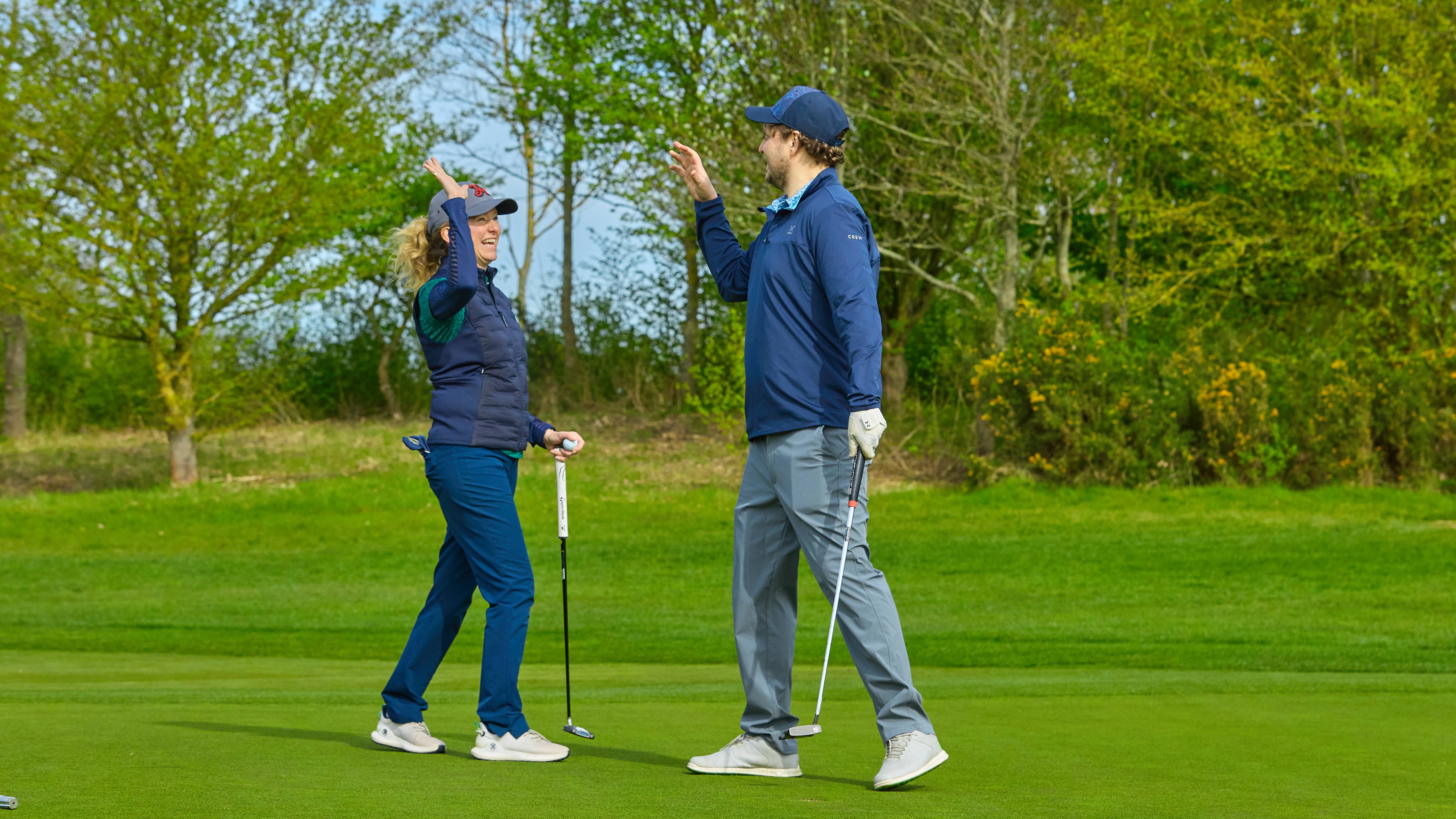 Golfers high fiving on the putting green