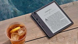 Amazon Kindle Oasis on a wet wooden deck beside a glass of cold drink