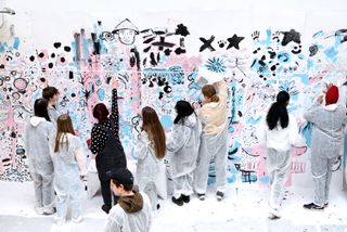 Group of people in white overalls painting a wall