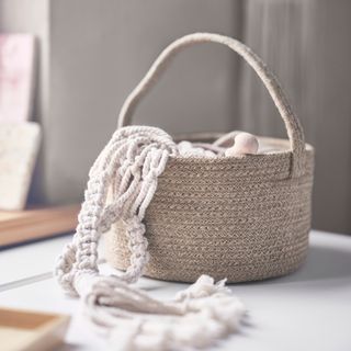 Jute bag with a handle with knitting spilling out, on top of a white surface in a calming white room