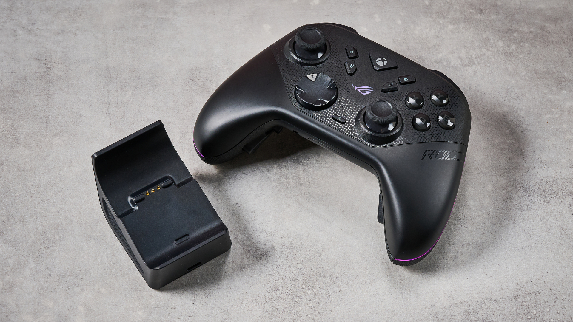 The Asus ROG Raikiri II Xbox Wireless and its dock sat on a stone-effect surface.
