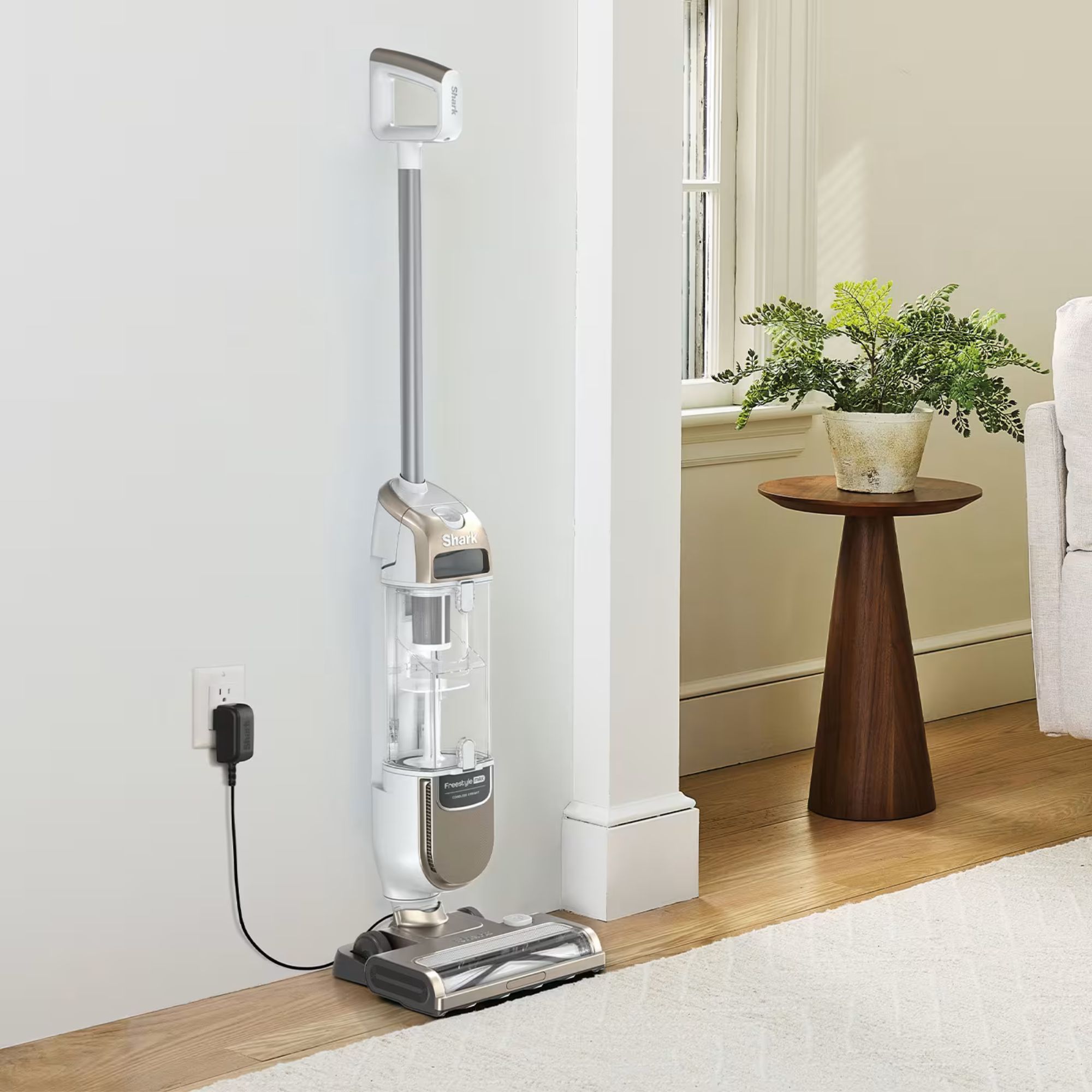 Shark Freestyle Pro vacuum cleaner plugged in in a white painted living room