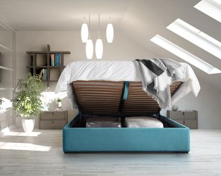 Teal raised top ottoman storage bed in white loft bedroom, with skylights.