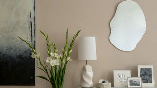 neutral brown wall with asymmetrical mirror and artwork