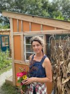 Woman holding a posy of flowers in front of wooden shed in a garden