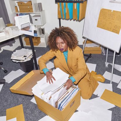 Woman organizing documents in cluttered office workspace
