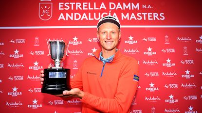 Adrian Meronk smiles as he holds up the 2023 Andalucia Masters trophy at Real Club de Sotogrande