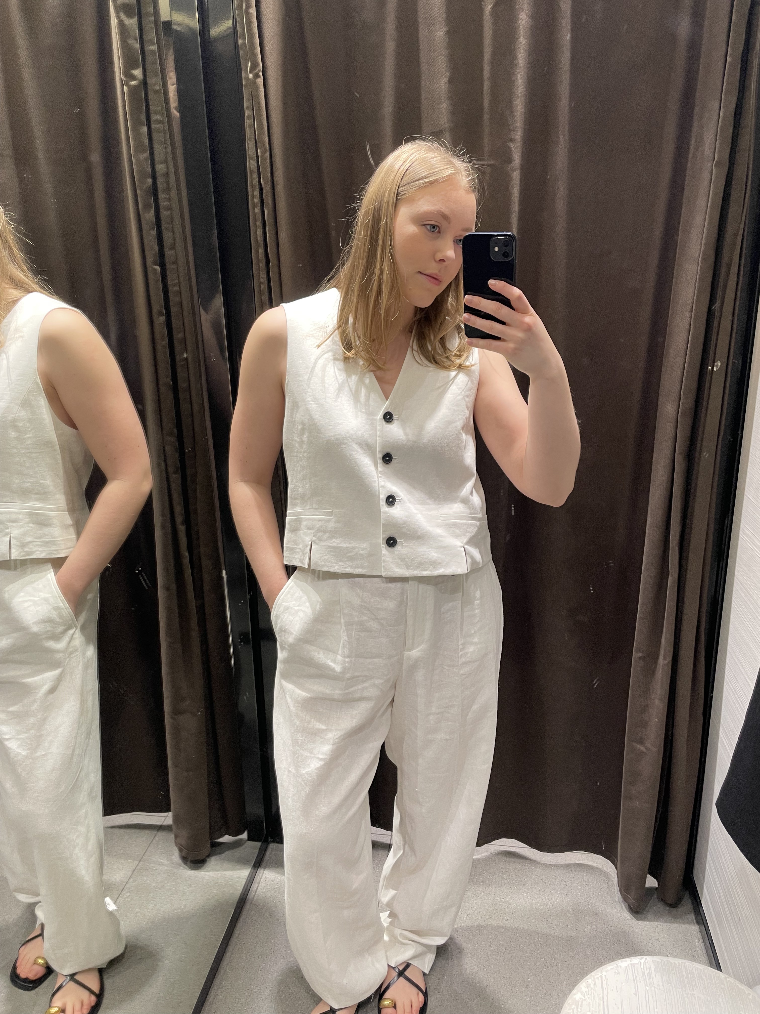 Woman in dressing room wears white linen waistcoat and trousers
