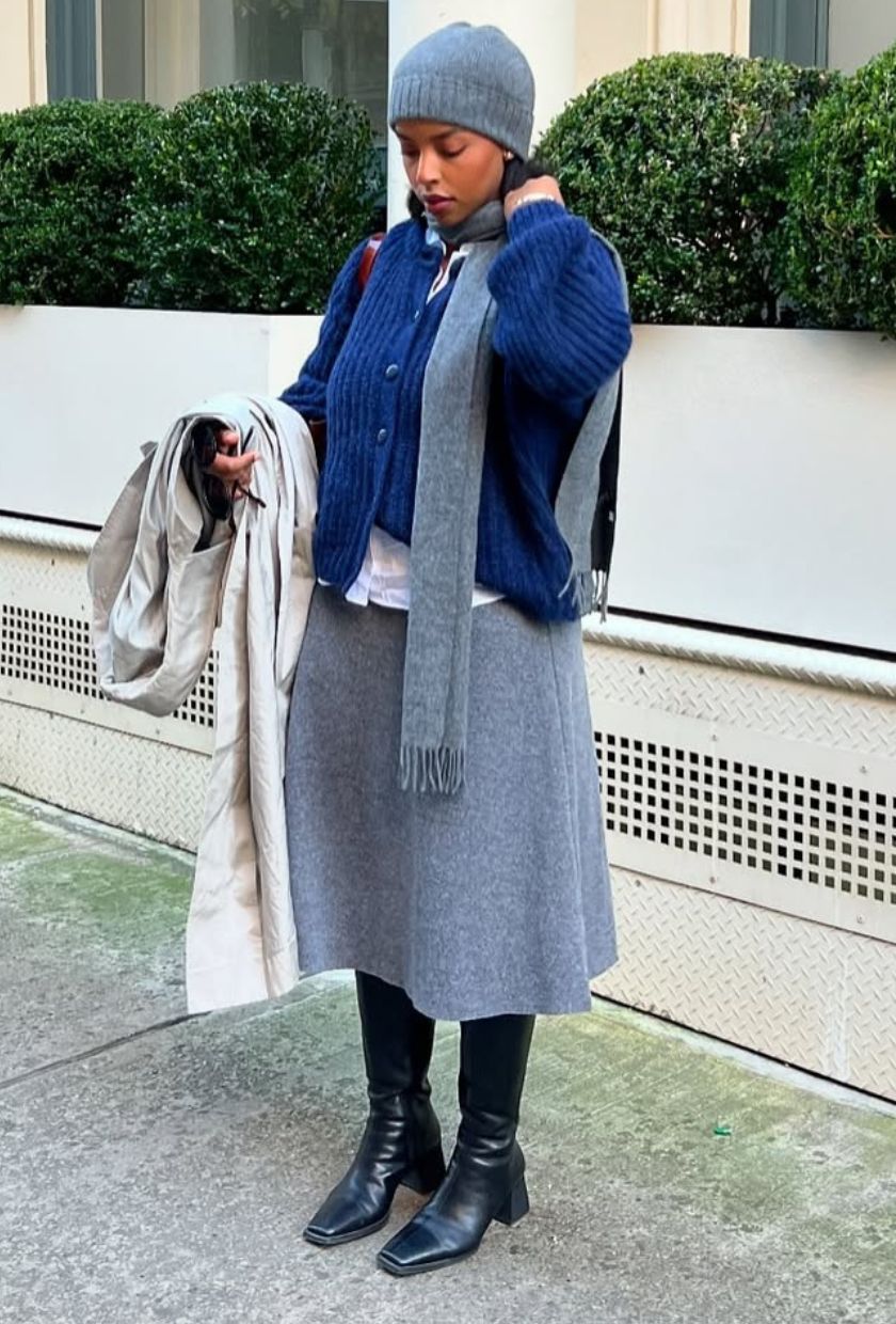 @aysha.sow wears a grey wool skirt with a blue cardigan, black boots and grey knitted accessories