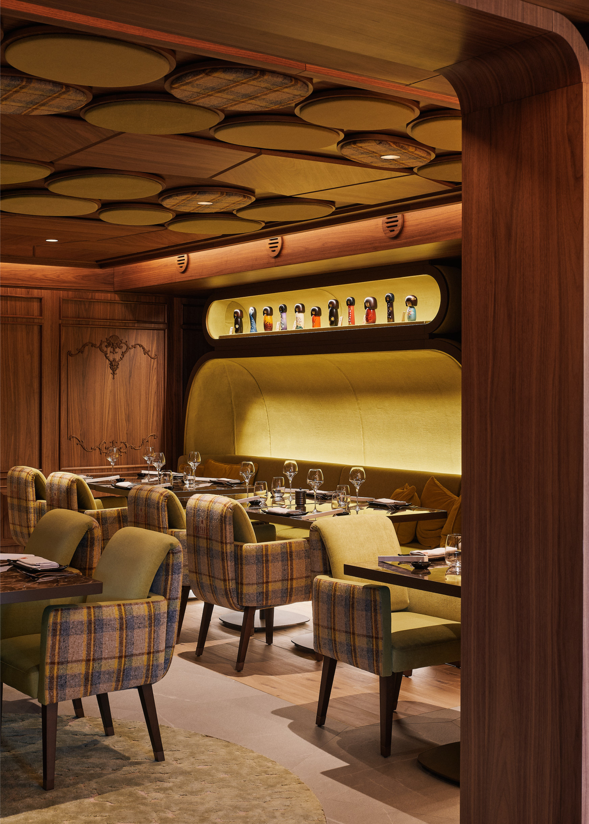The restaurant at Maya Hotel Courchevel with a green color scheme mixed with wood, with tartan armchairs, a backlit banquette seating area with a backlit alcove shelf above with decorative items and round circular details are attached to the ceiling