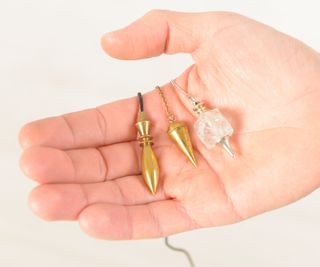 hand holding three different types of dowsing pendulums