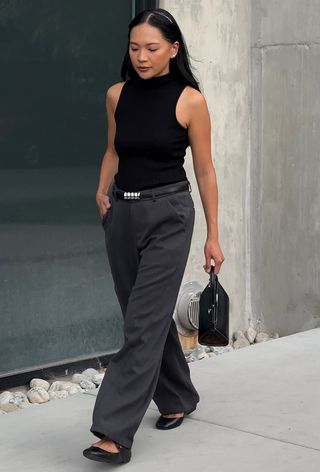 best elevated basics shown in a photo of a woman wearing a black turtleneck with gray trousers, a black belt, and ballet flats