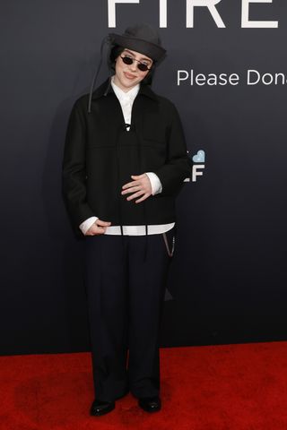 Billie Eilish wearing a sailor hat, a blazer, white button-down, and trousers on the 2025 grammys red carpet