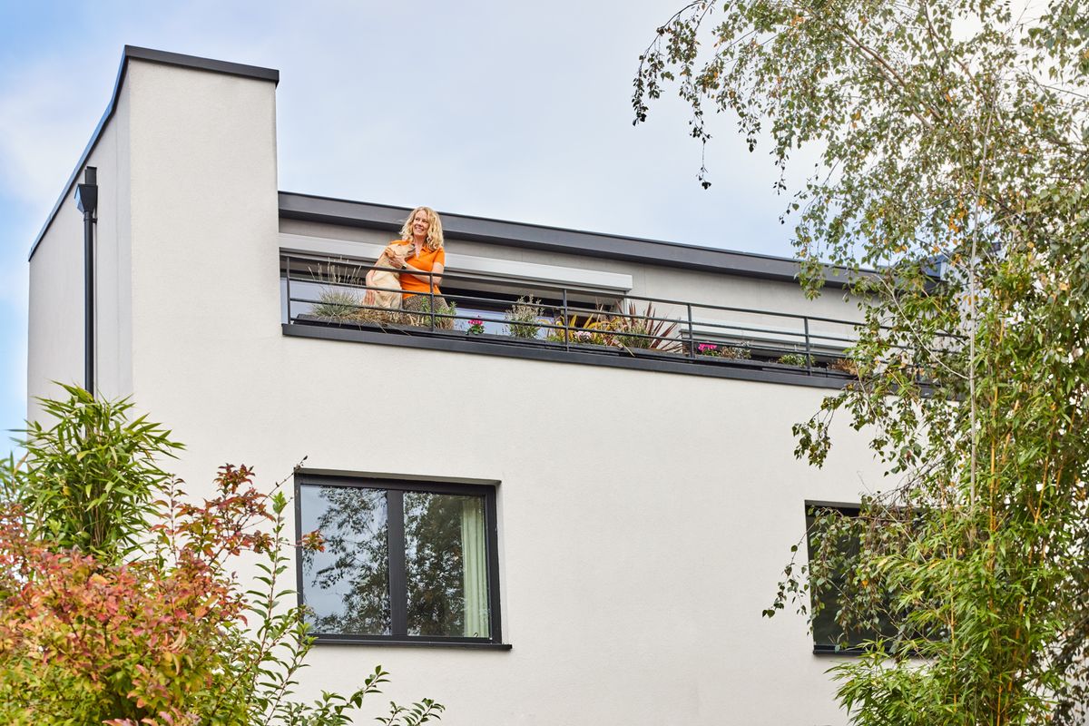 A woman and her Labrador stand on the outdoor balcony of her modernist home