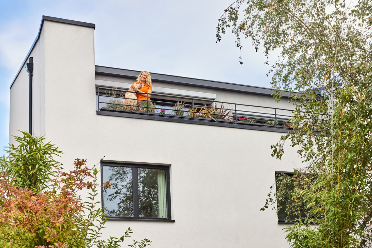 A woman and her Labrador stand on the outdoor balcony of her modernist home