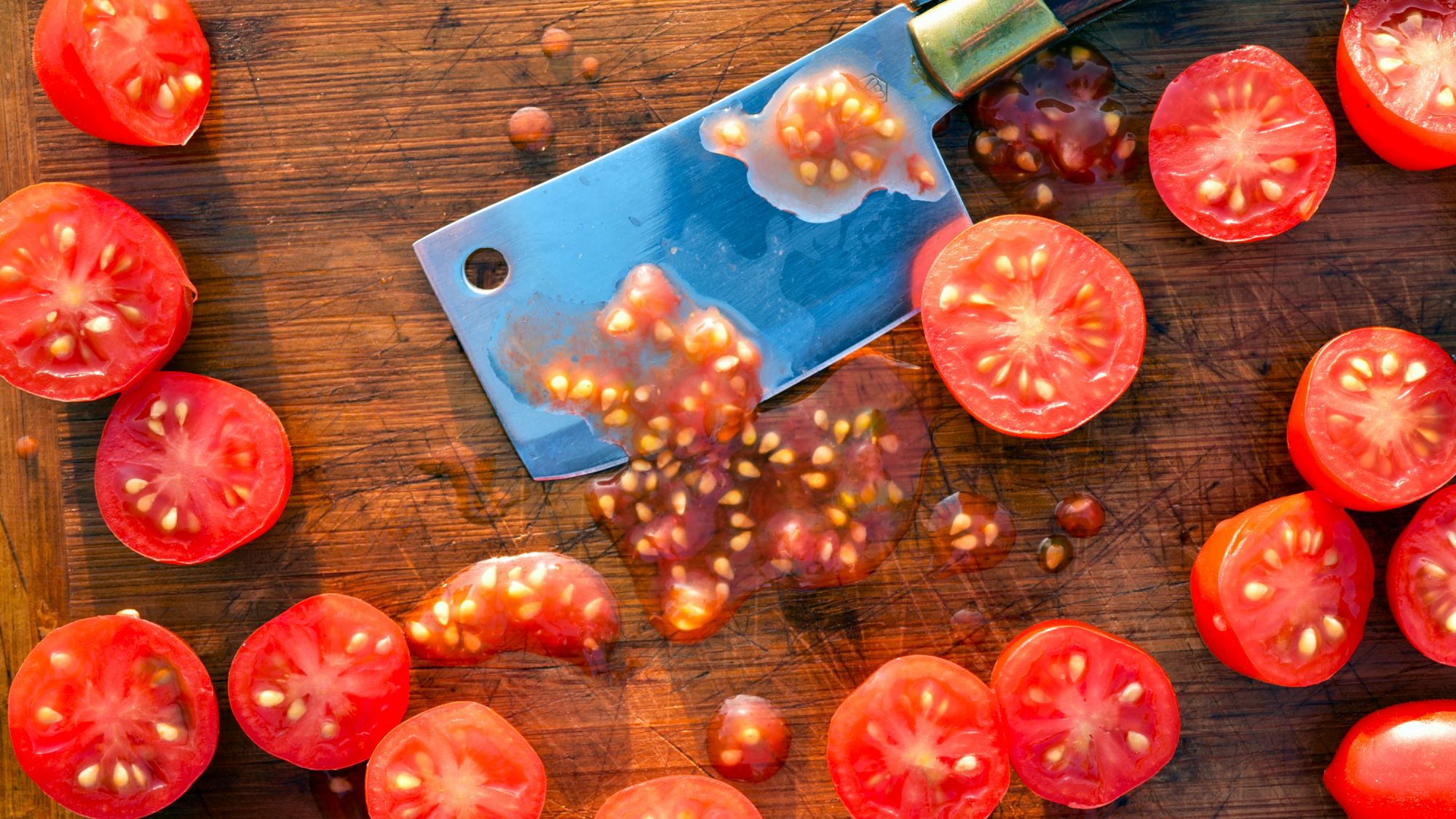 flat lay overhead view of kitchen still life scene close-up details of small grape tomatoes cut into halves with mini cleaver knife blade to extract seeds 