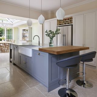 Grey kitchen island in large open plan kitchen with matching stools