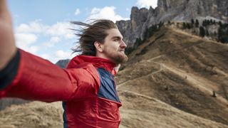 A hiker leans into the wind with his arms open