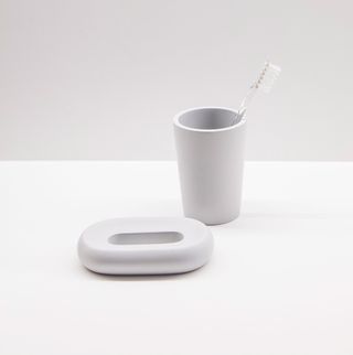 Refined bathroom accessories by Frédéric Périgot. A soap holder and a toothbrush cup made from smooth grey stone.