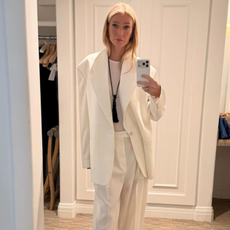 Gwyneth Paltrow takes a mirror selfie wearing a white oversized suit with white pointed-toe heels.