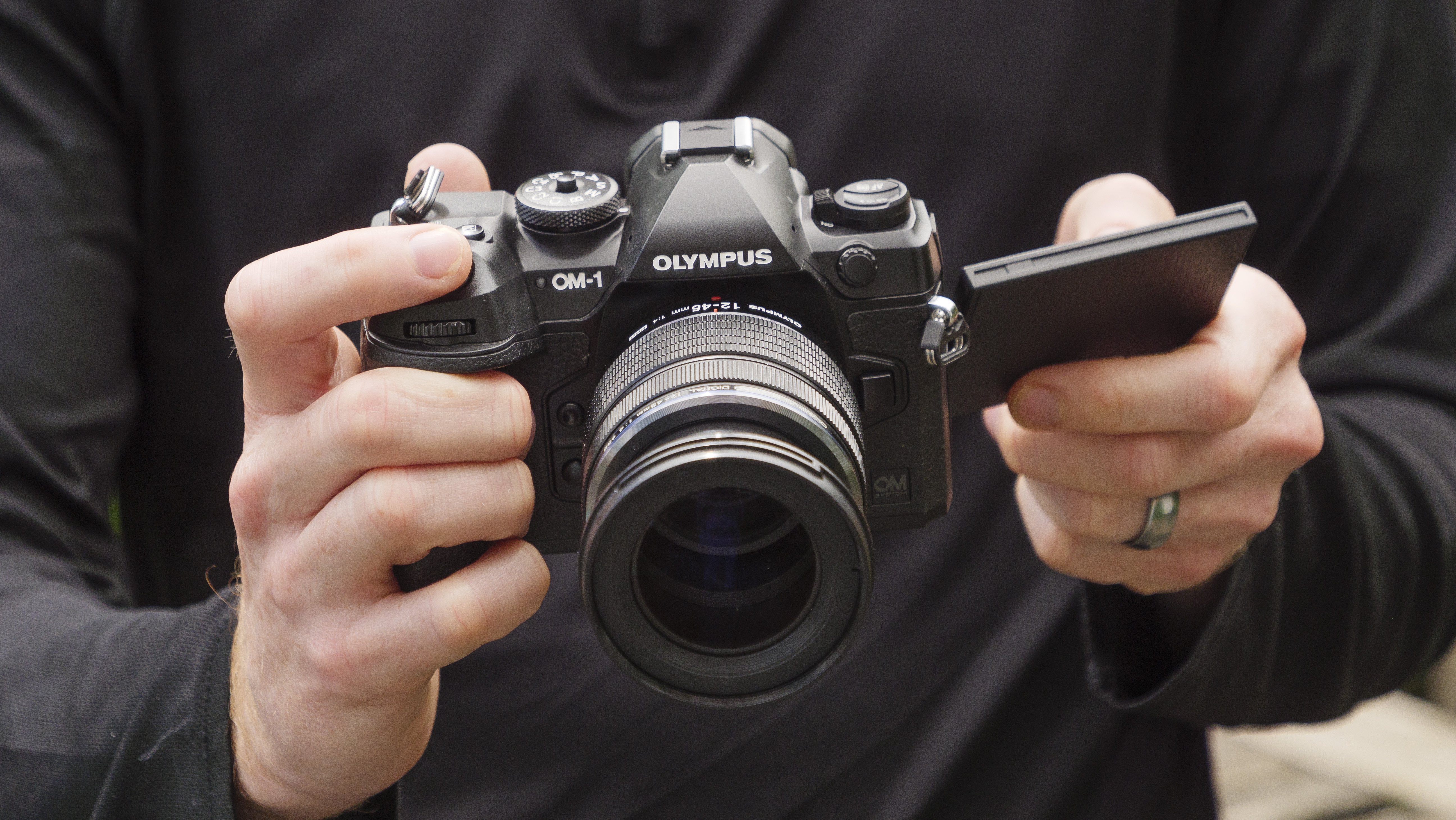 A person's hands holding the OM System OM-1 camera