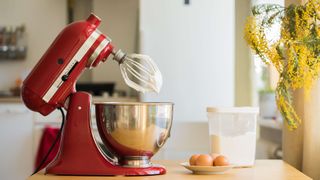 KitchenAid red stand mixer with a whisk attachment covered in egg white
