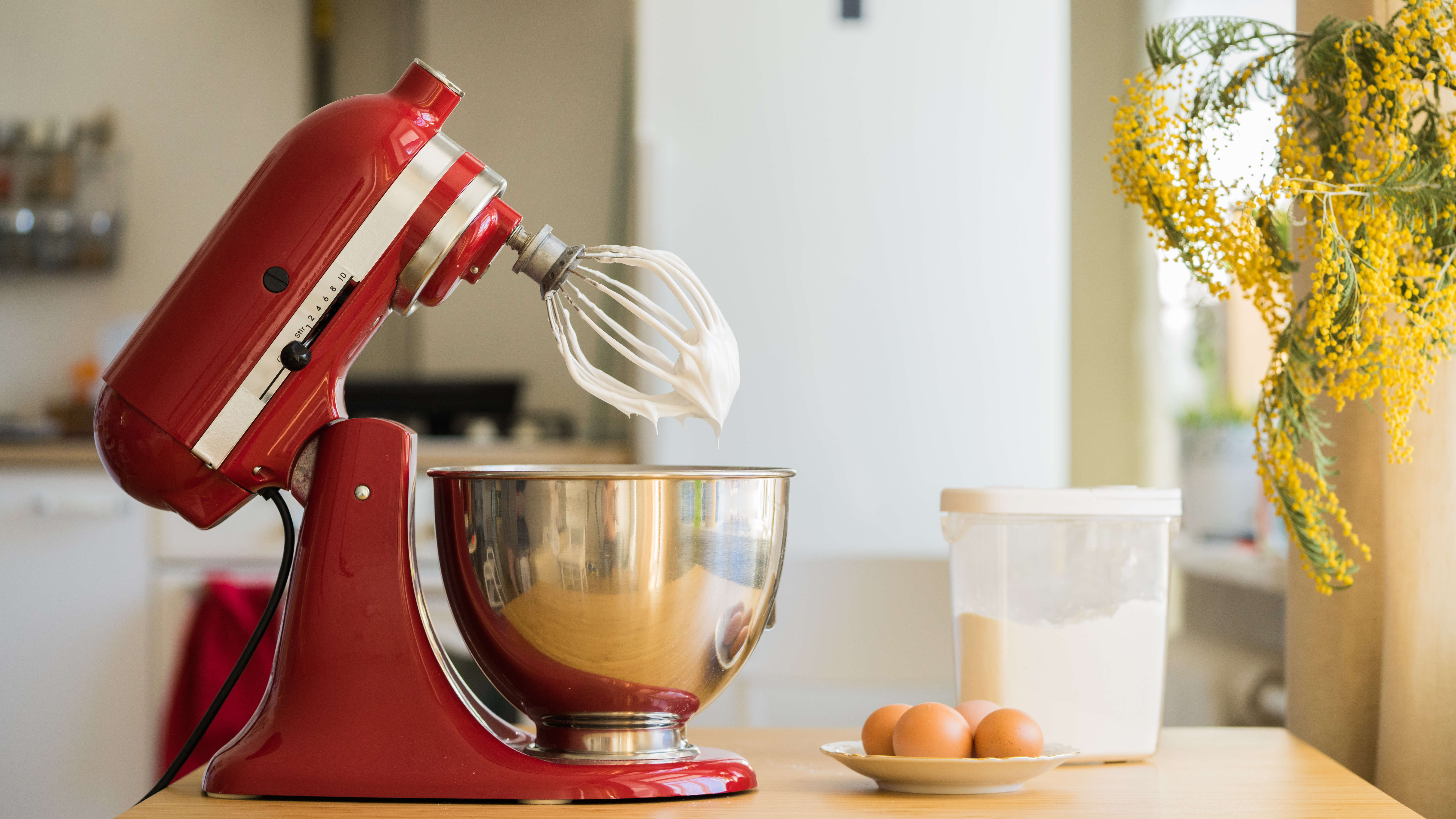 KitchenAid red stand mixer with a whisk attachment covered in egg white
