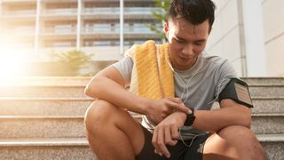 What are cardio heart rate zones? image shows fitness tracker and heart rate monitor: image shows runner on steps looking at fitness tracker