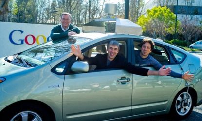 Google executives Eric Schmidt, Larry Page, and Sergey Brin pose in their self-driving test model car.