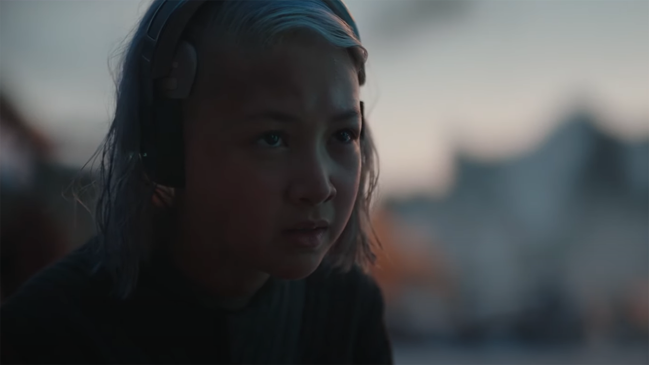 A close-up of a young girl with grey hair and cybernetic implants on her head.