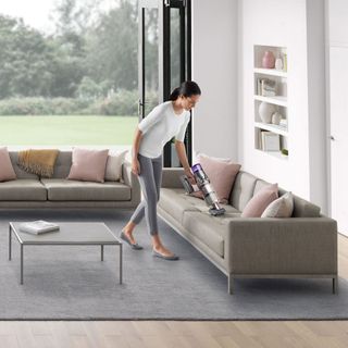 Living room with vaccum cleaner women and sofa set with cushion