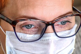 Close-up of a woman wearing glasses and a face mask.