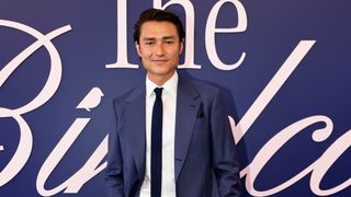 Neighbours star Tim Kano poses for a photo during 2024 Melbourne Cup Day at Flemington Racecourse in Melbourne, Australia, wearing a blue suit and tie with a white shirt. 