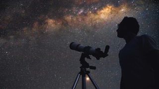 Man and telescope against milkyway backdrop