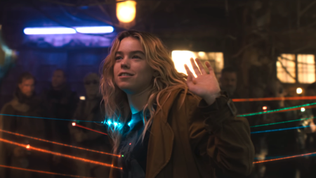 Milly Alcock as Kara with her hands up as lasers point at her in Supergirl