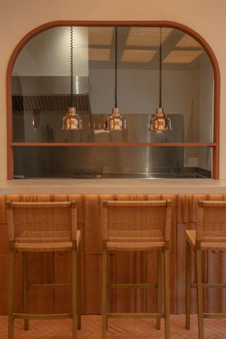 A softly lit restaurant features a show kitchen with wooden and chrome finishings.