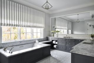 White bathroom with gray furniture and a gray and white striped blind