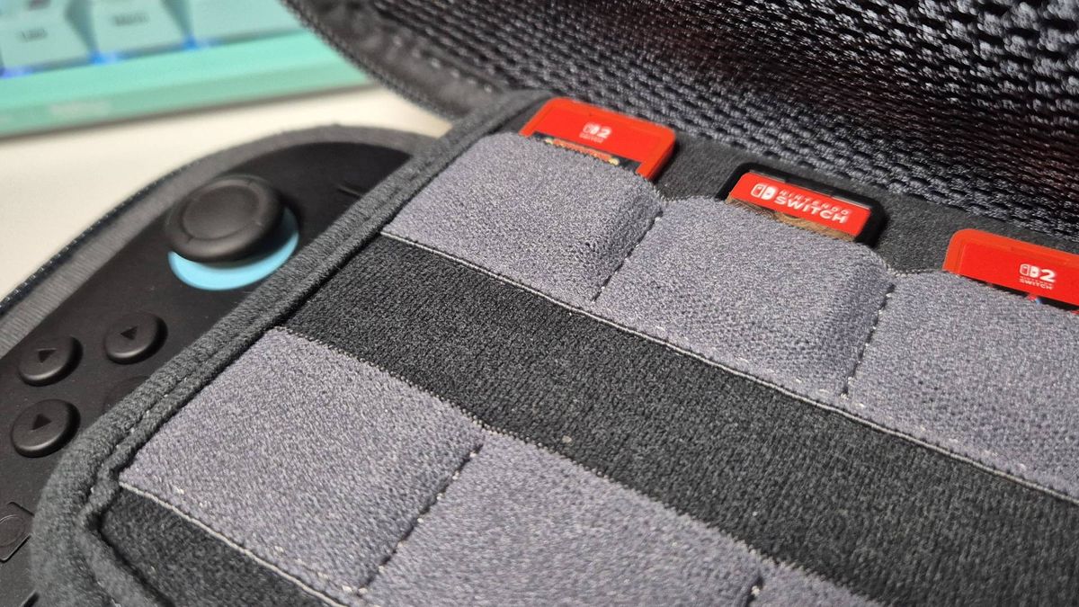 Photo of a close-up inside a Switch 2 case. There's two red Switch 2 cards and one older Switch 2 game sitting in some pockets, and you can see the Switch 2 peeking out underneath.