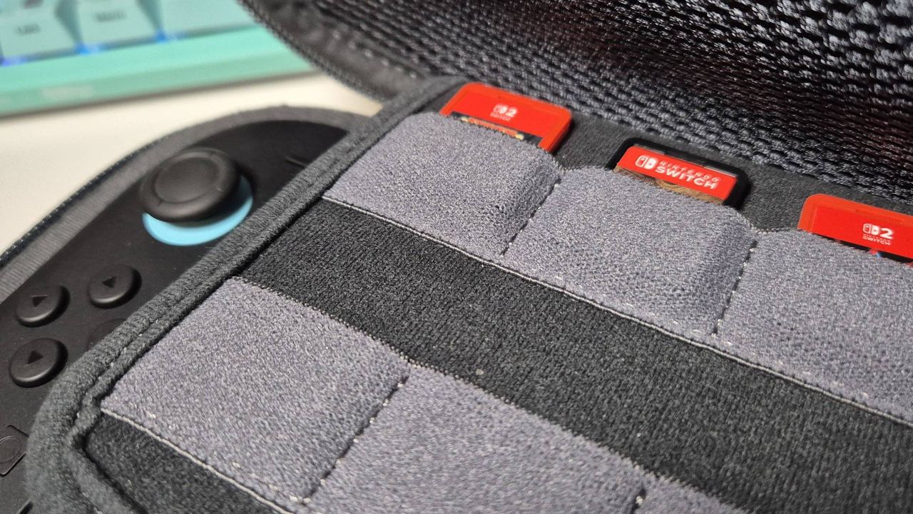 Photo of a close-up inside a Switch 2 case. There's two red Switch 2 cards and one older Switch 2 game sitting in some pockets, and you can see the Switch 2 peeking out underneath.