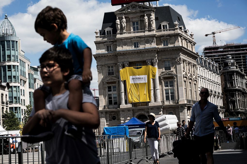 People pass by a giant Yellow Jersey hanging on a facade on July 3, 2019 in Brussels centre, three days prior to the start of the 106th edition of the Tour de France