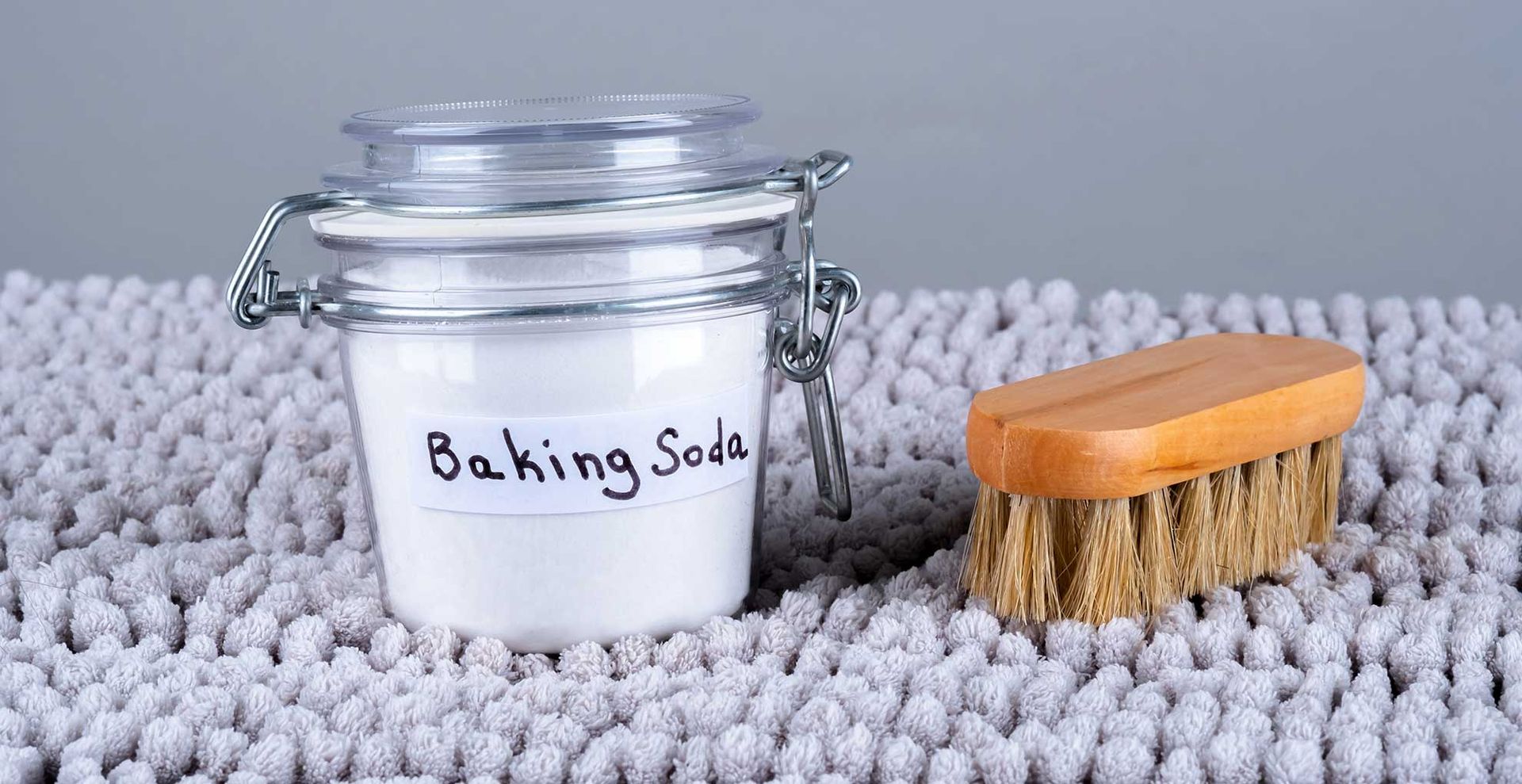 grey crpet with a jar of baking soda to suggest how to get rid of fleas