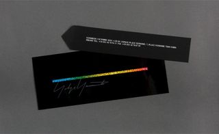 Alternative view of Yohji Yamamoto's invitation featuring a separate strip with the event details. The invitation is pictured against a grey background