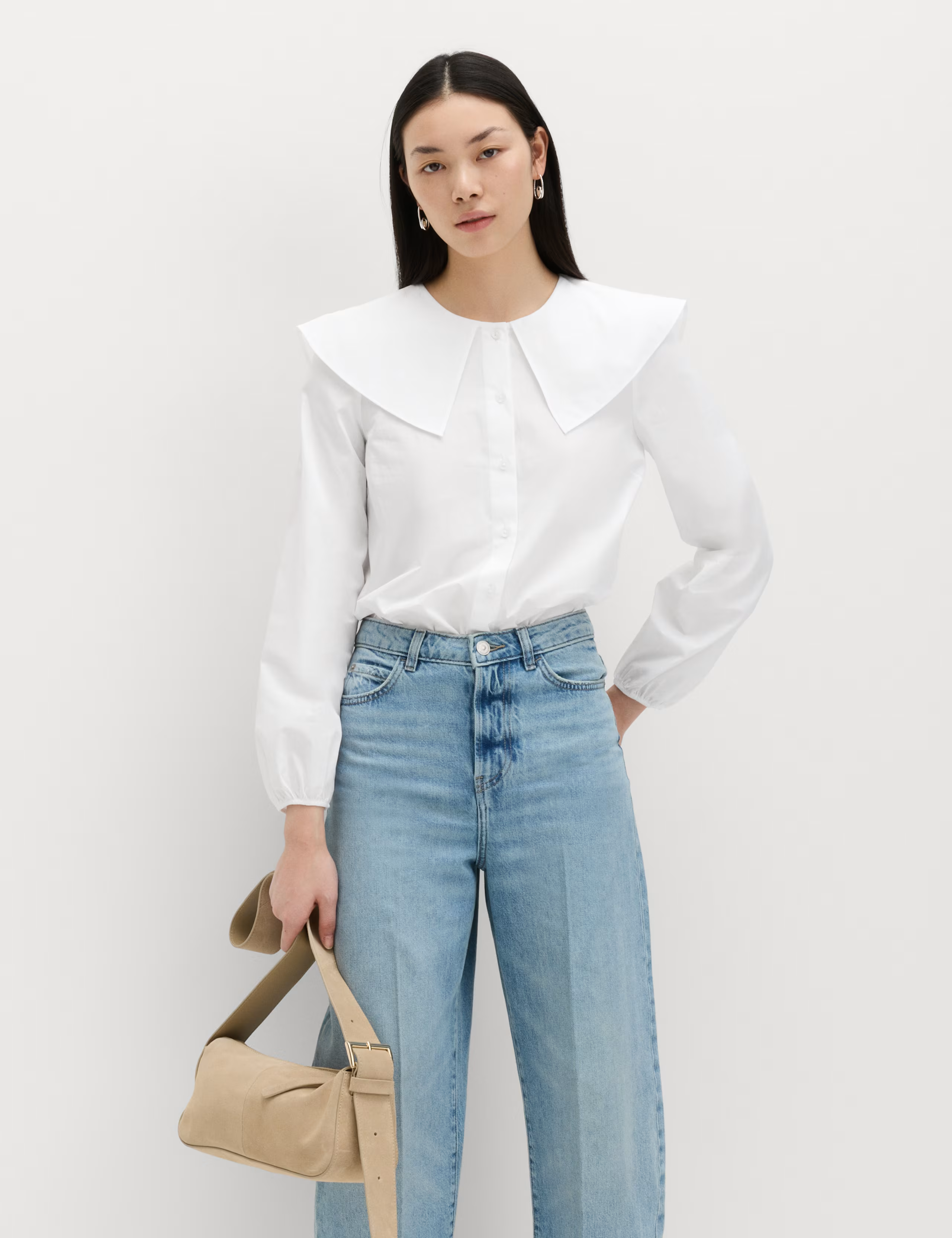 A model wearing a white collared blouse.