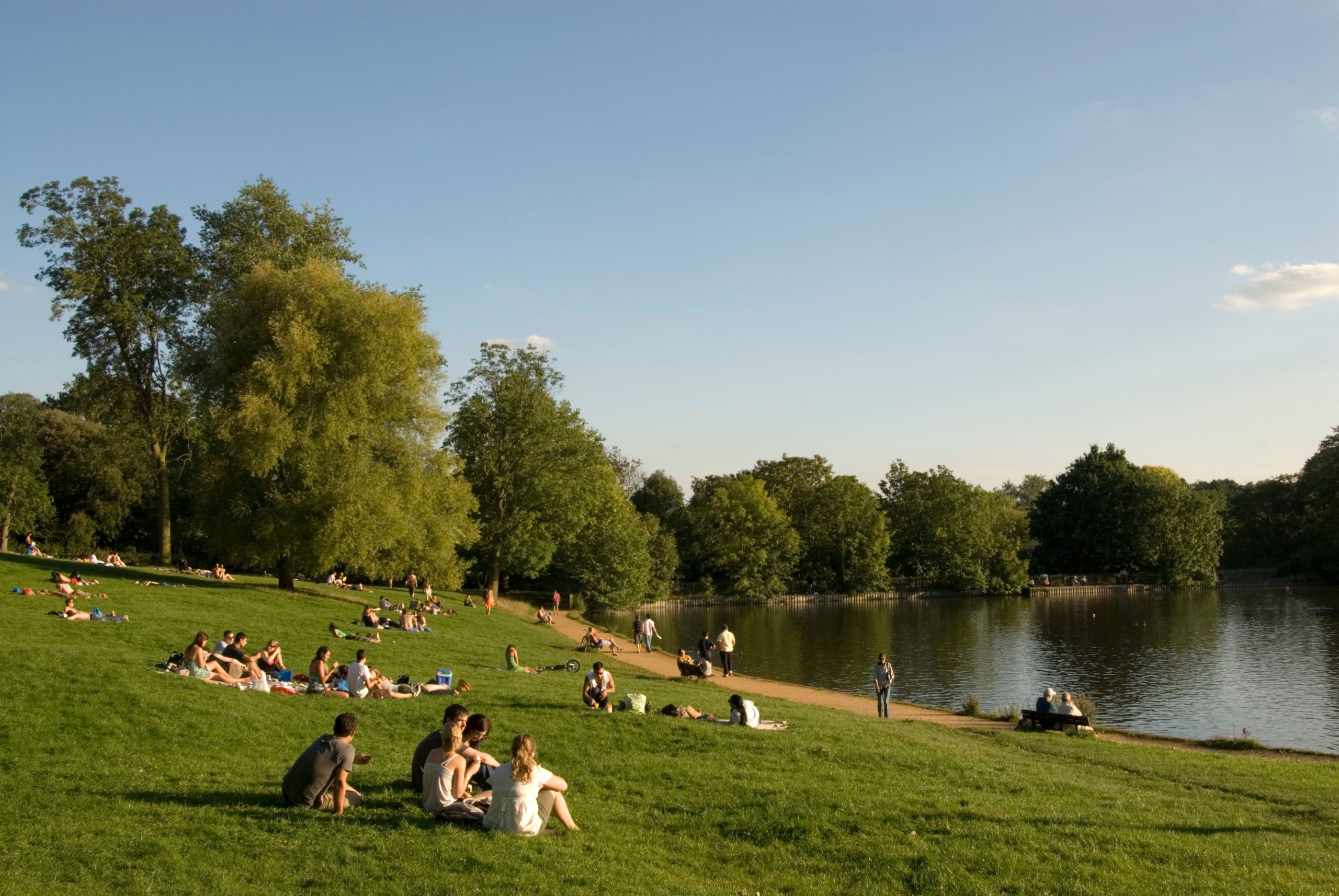 Young people relaxing beside Highgate pond on Hampstead Heath,